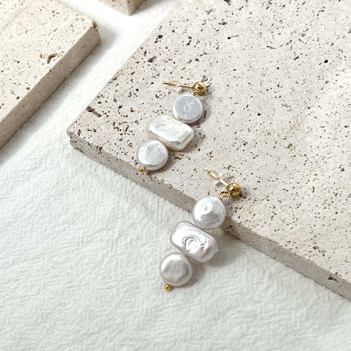Close-up of 14K gold baroque pearl dangling earrings, minimalist and dainty craftsmanship