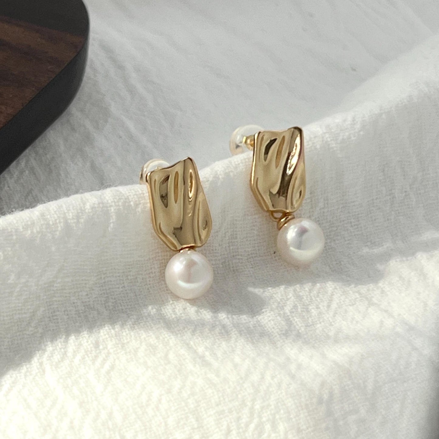 Close-up of baroque freshwater pearl detail on 18K gold earrings