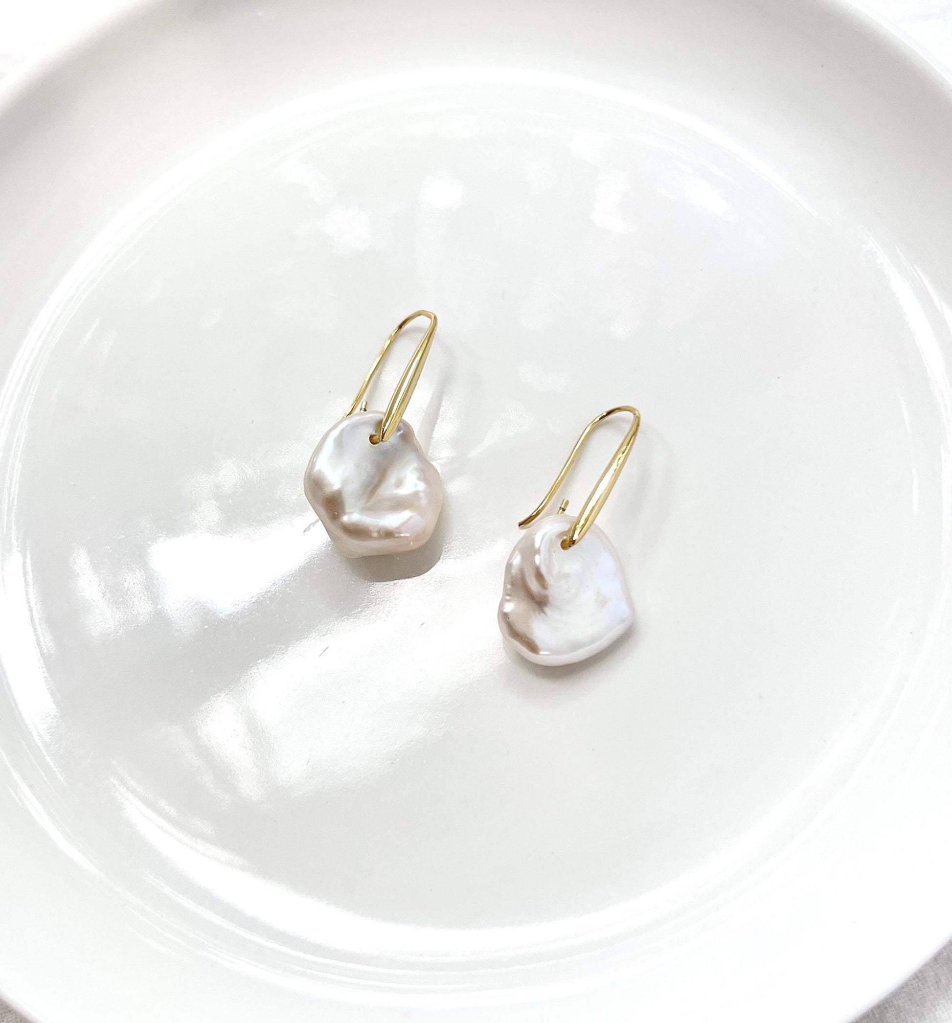Side view of 18K gold baroque pearl hoop dangle earrings