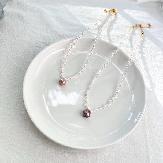 Two pearl necklaces on a white plate with a white background