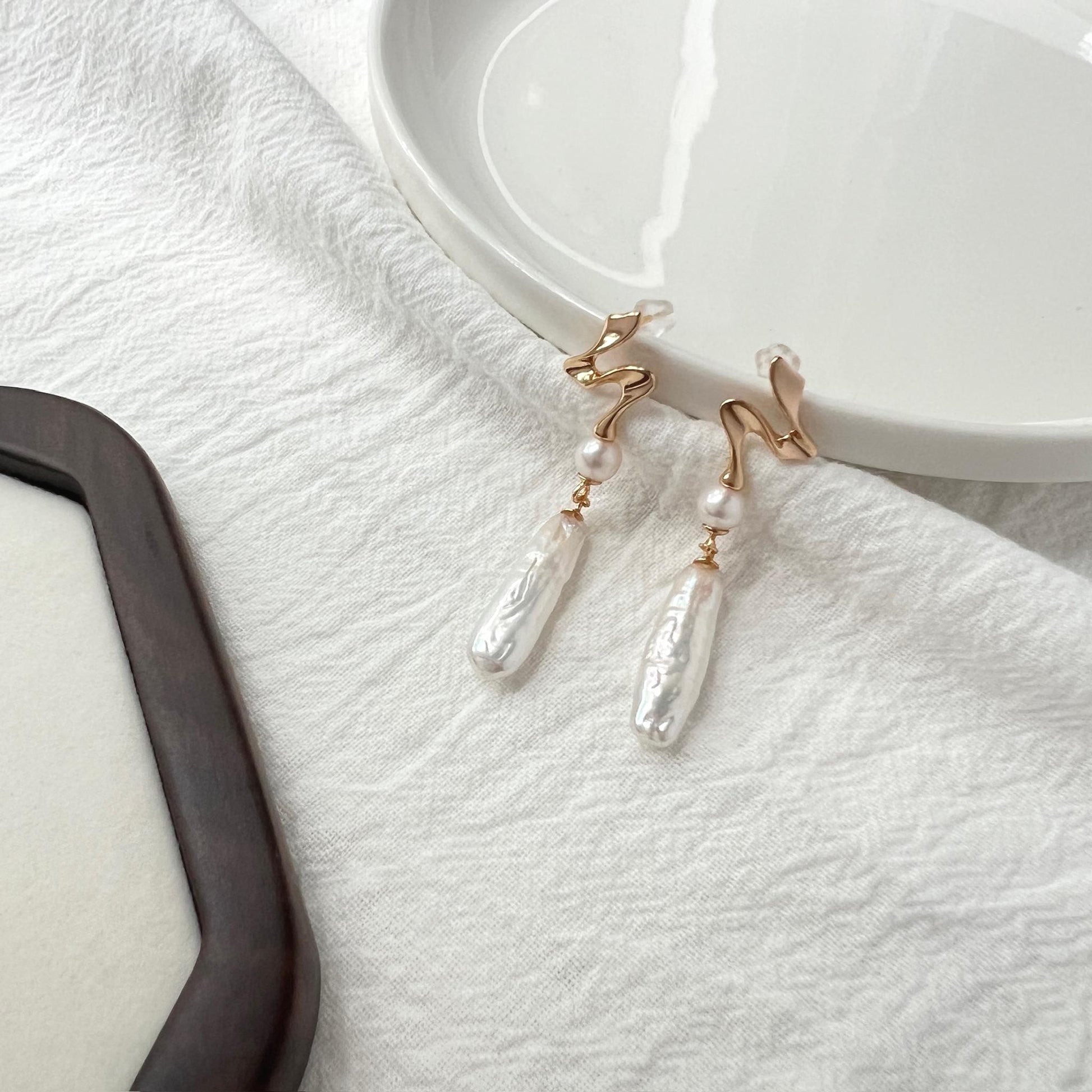 Close-up of baroque freshwater pearls on 18K gold bar drop earrings