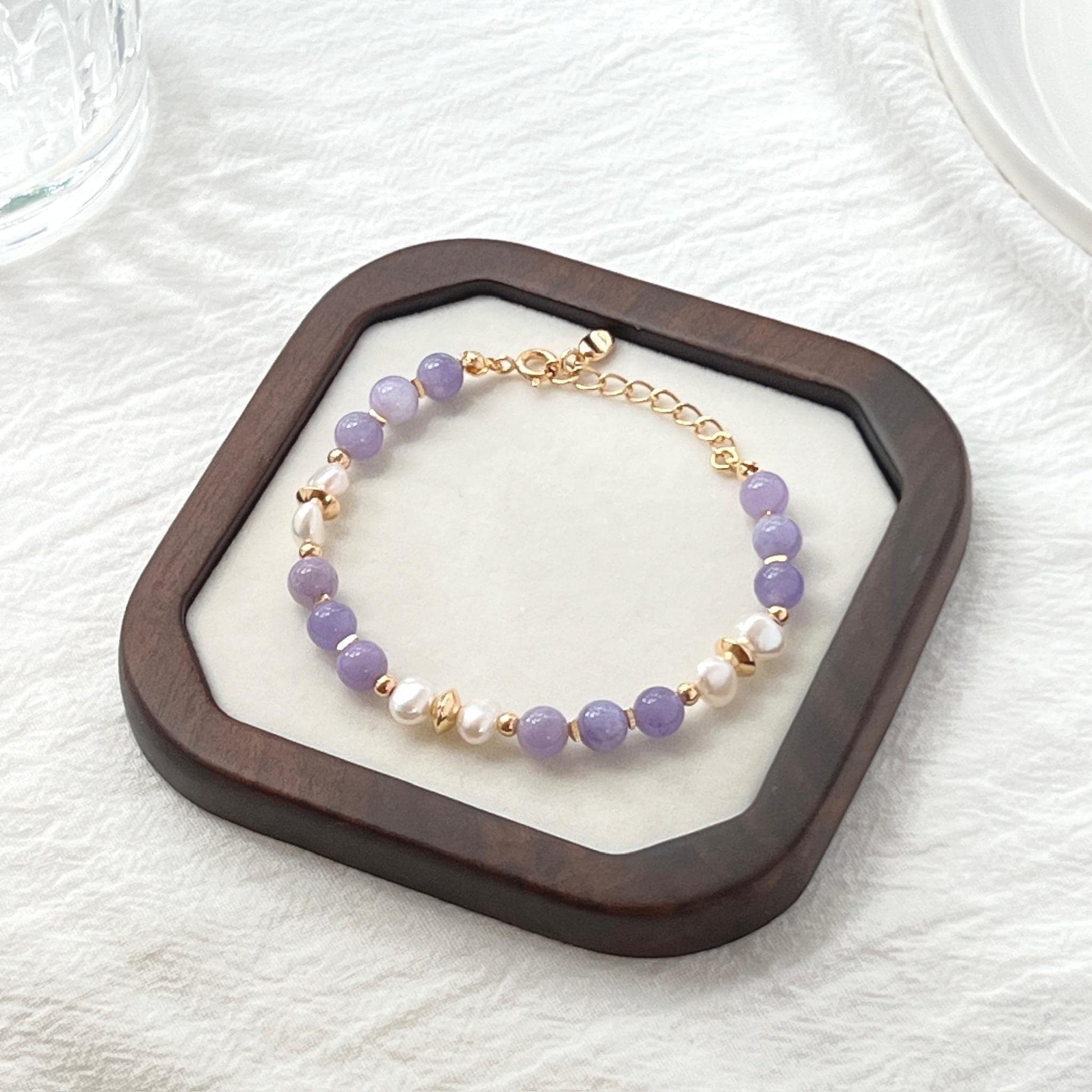 Close-up showing natural baroque pearls and lilac lepidolite gemstones on 18K gold bracelet