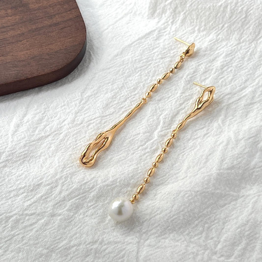 Close-up of natural freshwater pearls on 18K gold long drop mismatched earrings