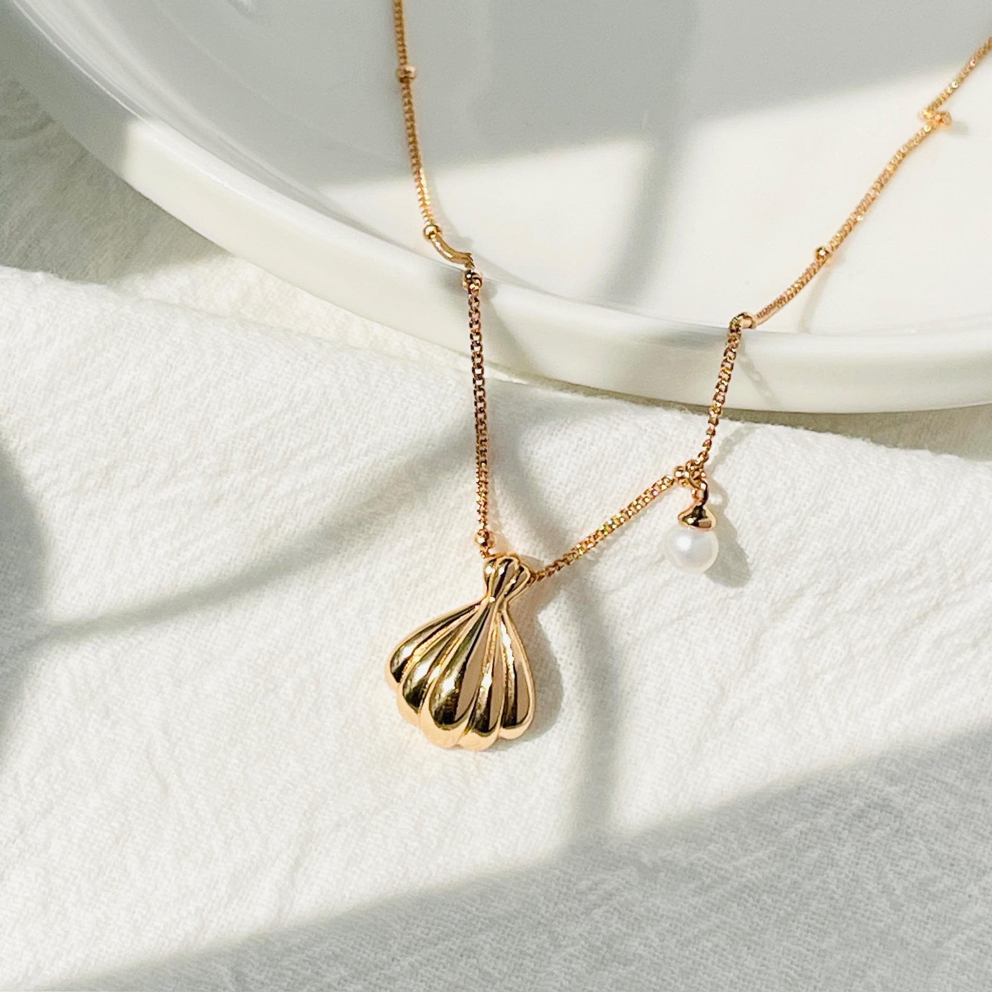 Close-up of the 18K gold shell pendant with freshwater pearl detail