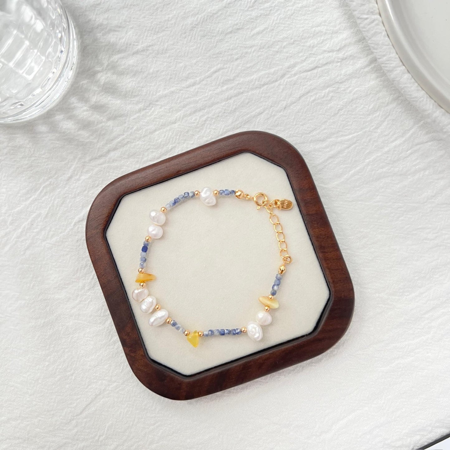Model wearing 18K gold baroque pearl, lapis lazuli, and beeswax bracelet, minimalist style
