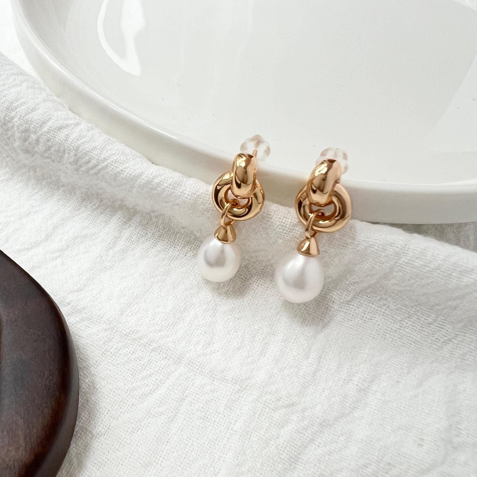 Model wearing 18K gold vintage pearl dangling earrings with Celtic knot design