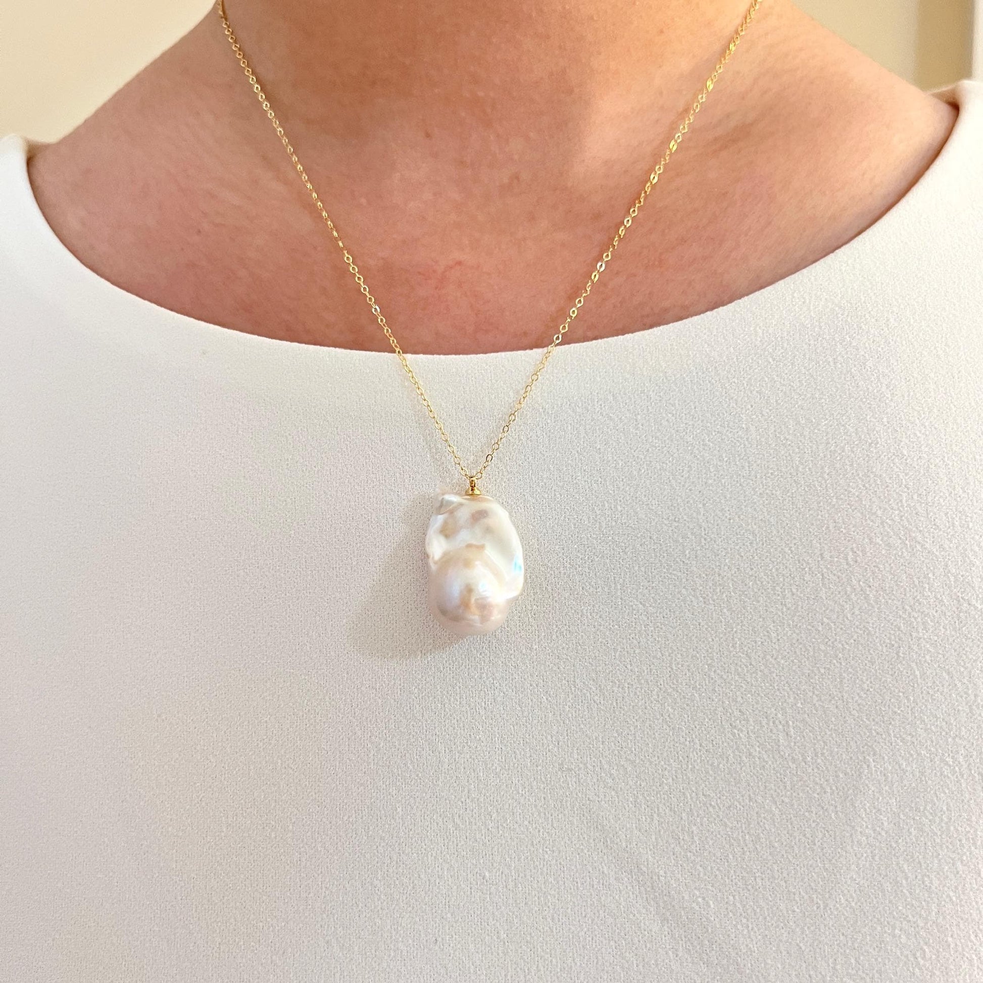 Model wearing 14K gold-filled necklace with large baroque pearl, statement style
