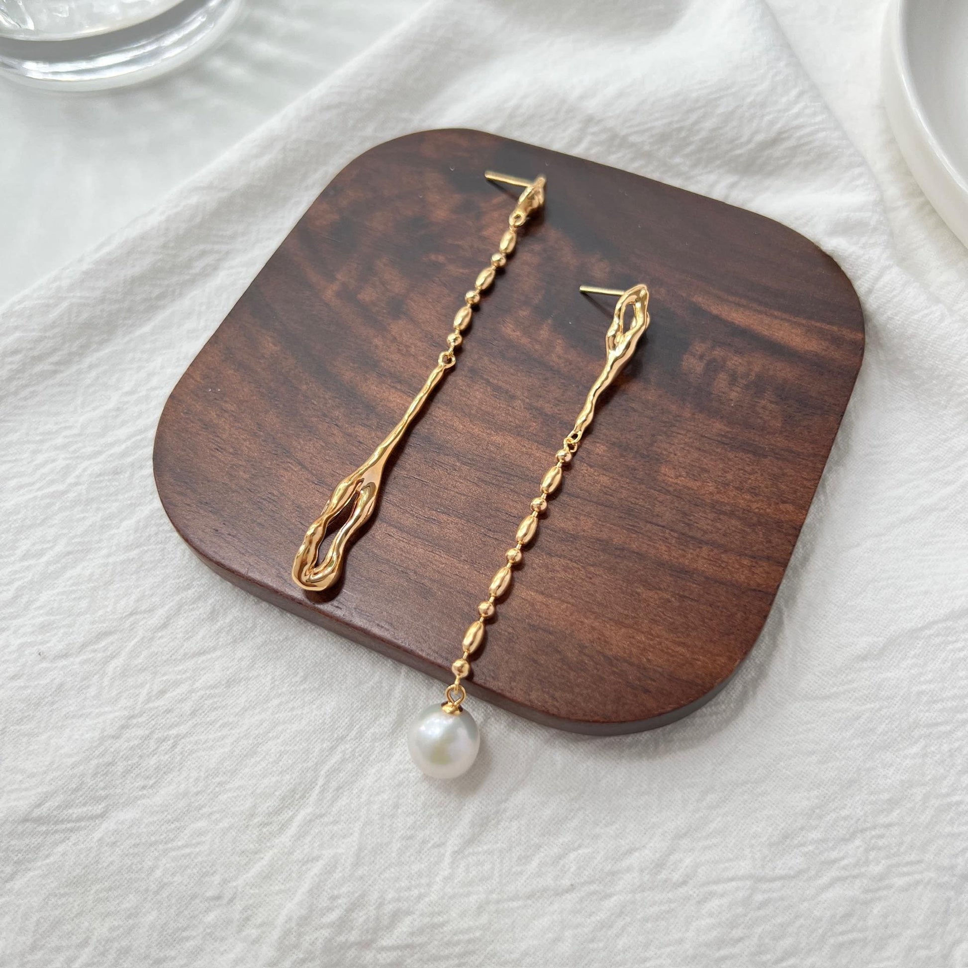 Side view of 18K gold mismatched long drop pearl earrings, minimalist design
