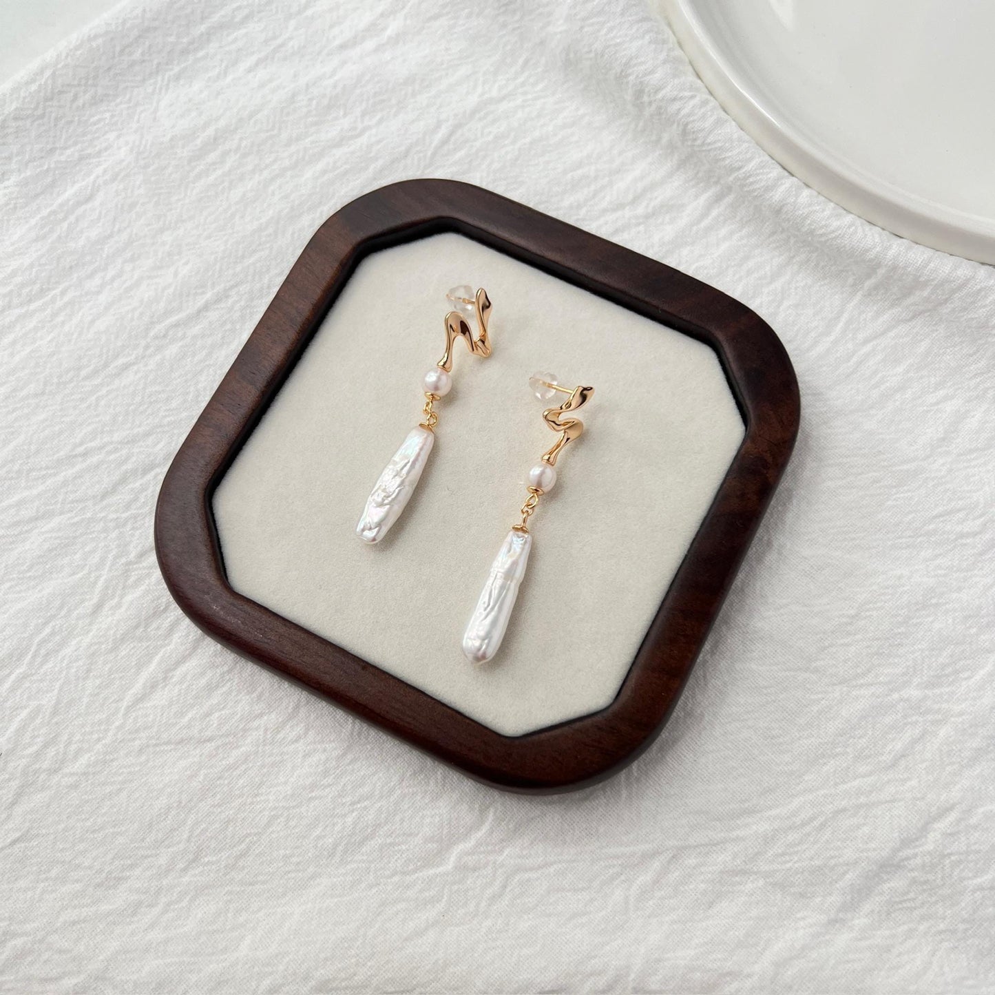 Side view of 18K gold baroque pearl bar drop earrings