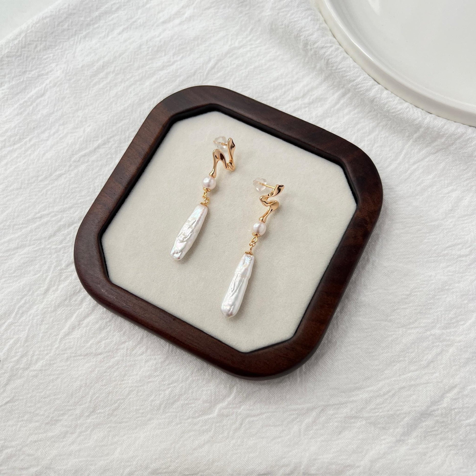 Side view of 18K gold baroque pearl bar drop earrings