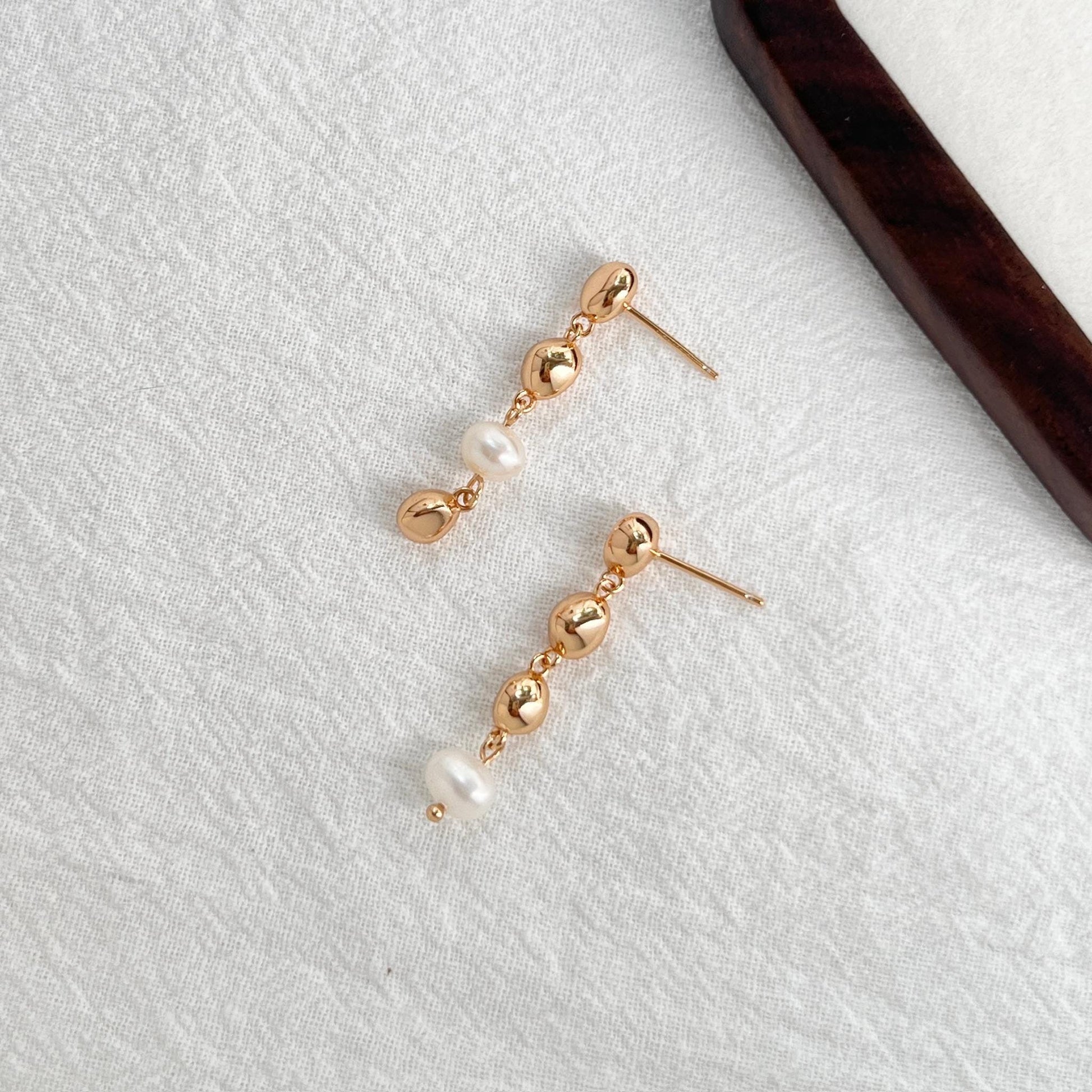 Side view of 18K gold beaded freshwater baroque pearl drop earrings