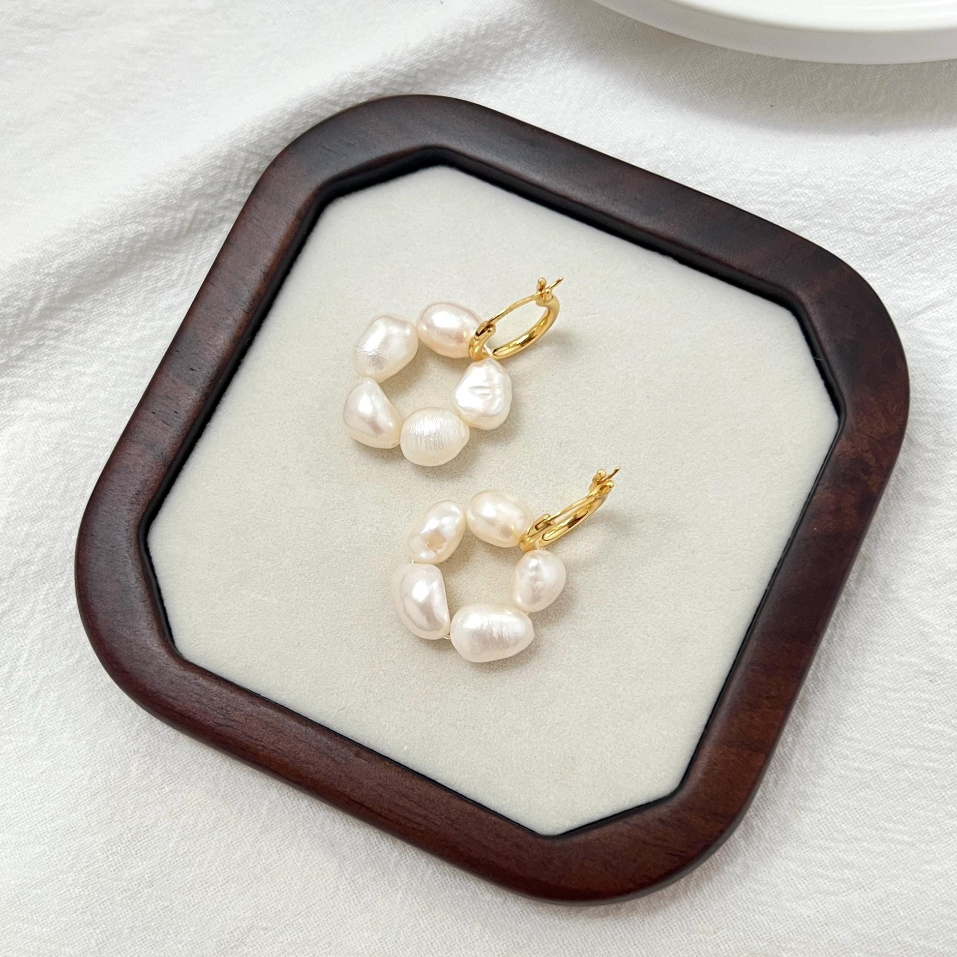 Close-up of 18K gold baroque pearl flower drop earrings, highlighting pearl and metal craftsmanship