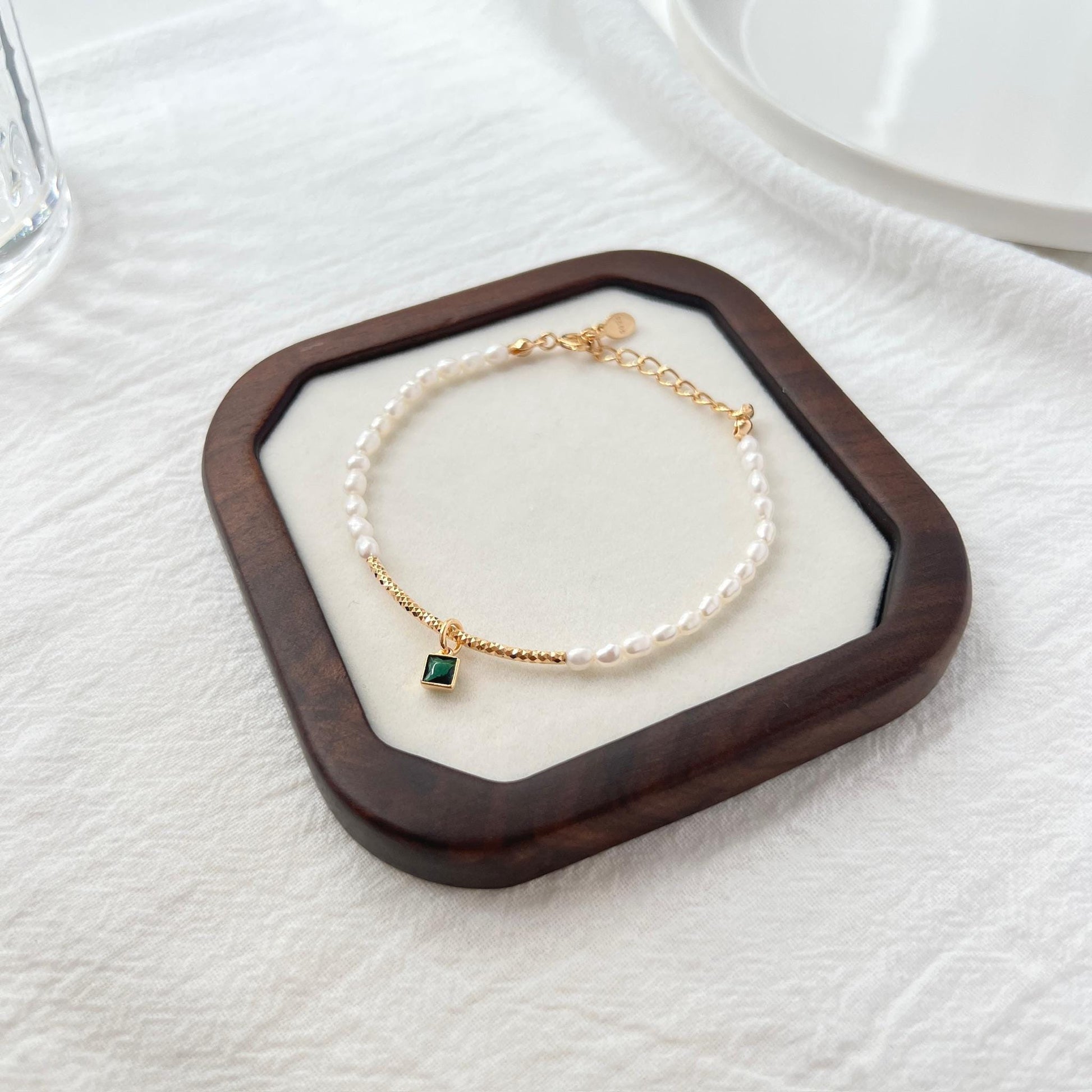 Close-up of natural baroque pearls and green zircon beads on 18K gold bracelet