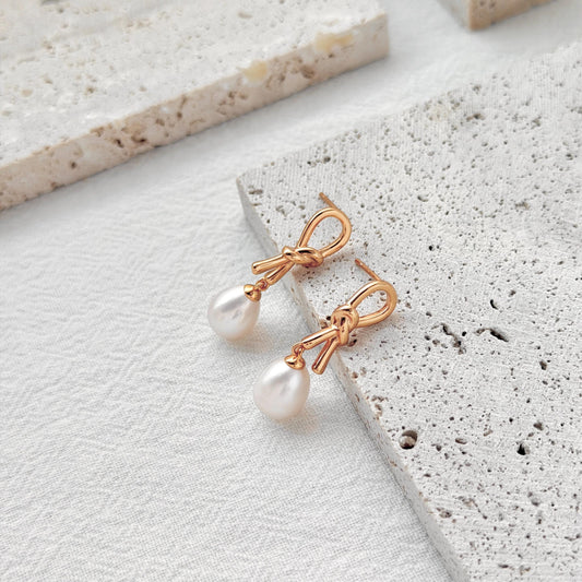 close up of 18k gold bow knot pearl drop earrings detailing and texture
