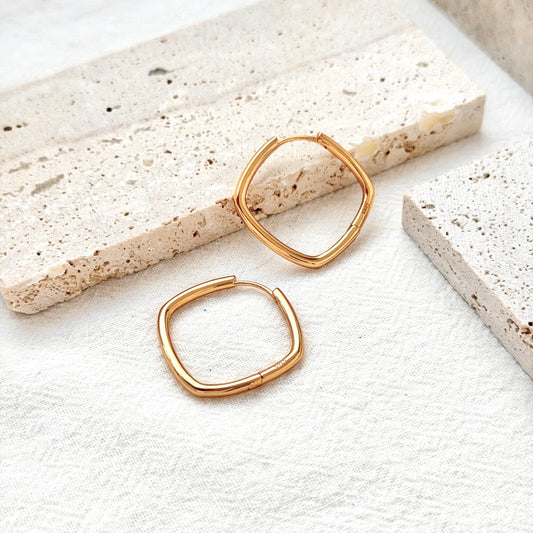 close up of geometric square huggie hoop earrings in 18k gold elegant finish