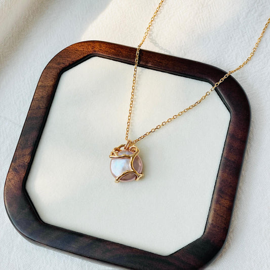 Close-up of baroque purple pearl and double-sided coin pendant on 18K gold necklace, dainty handmade jewelry.