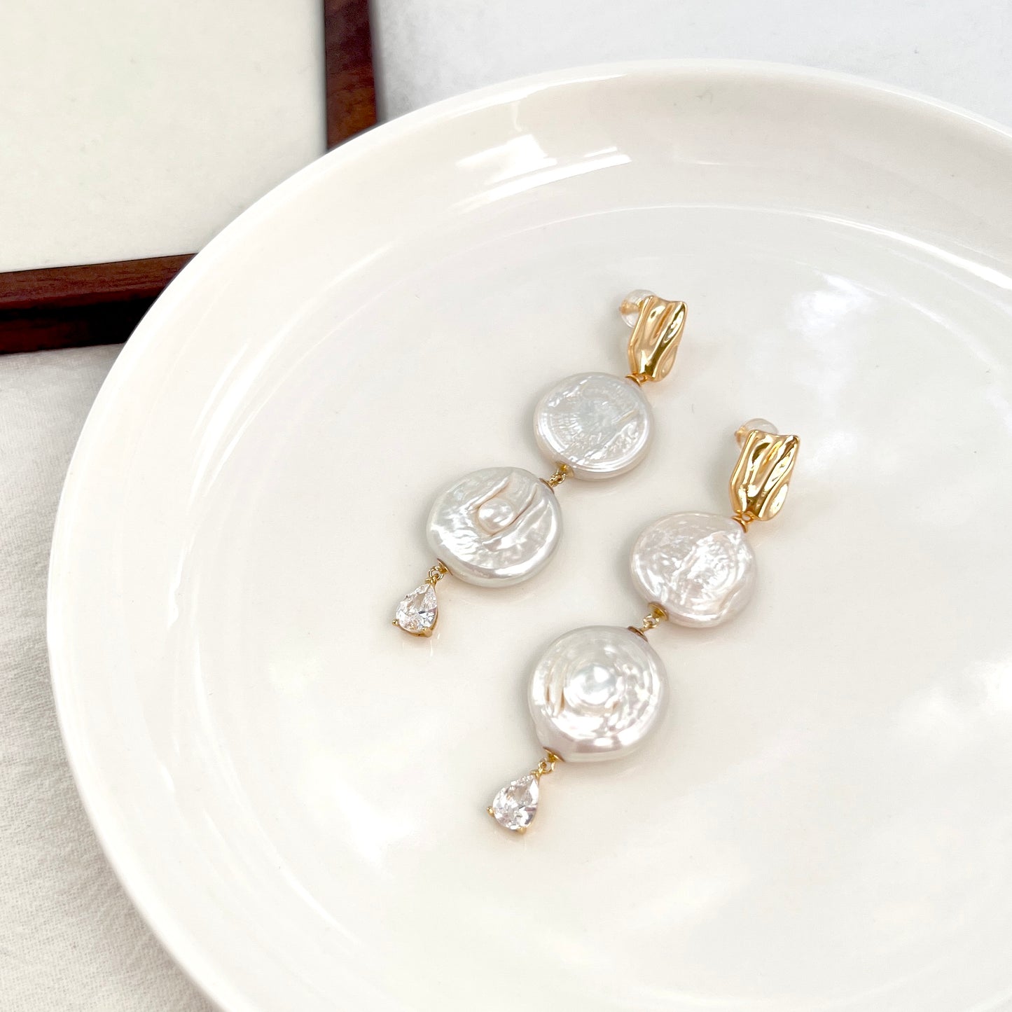 Close-up of Rome Coin pearl drop earrings, showing pearl texture and delicate craftsmanship