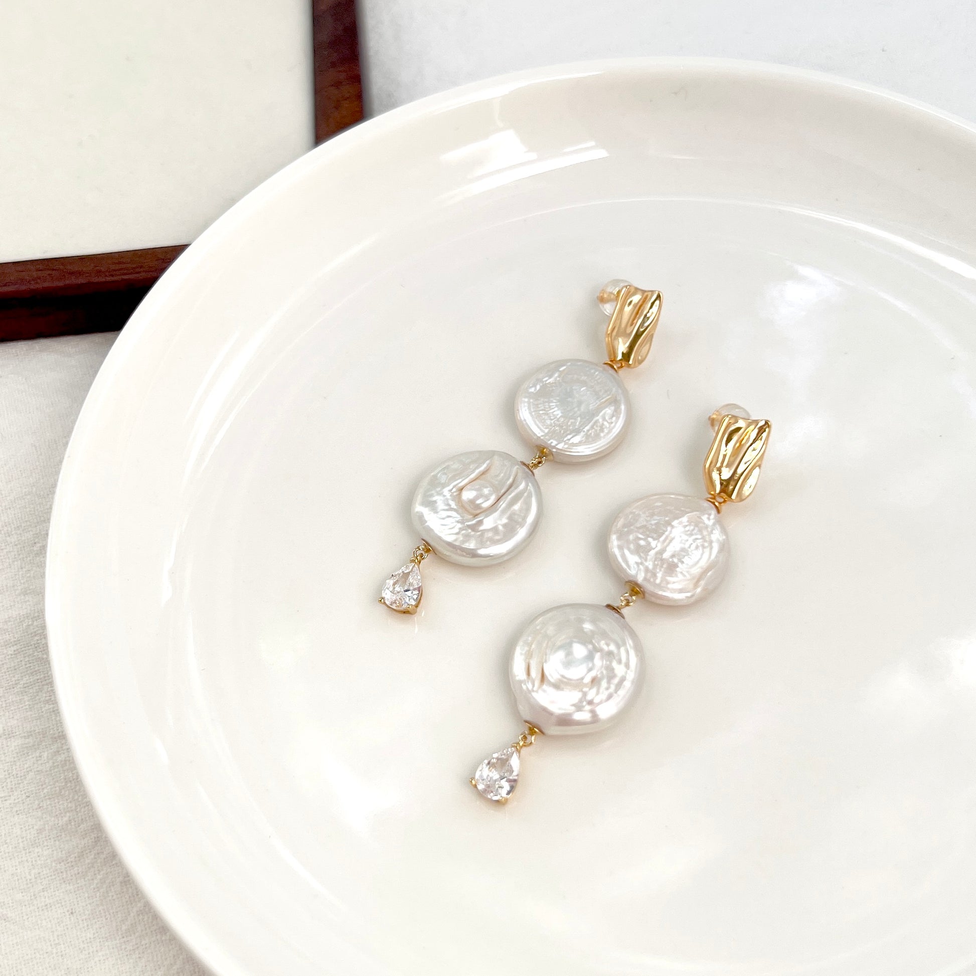 Close-up of Rome Coin pearl drop earrings, showing pearl texture and delicate craftsmanship
