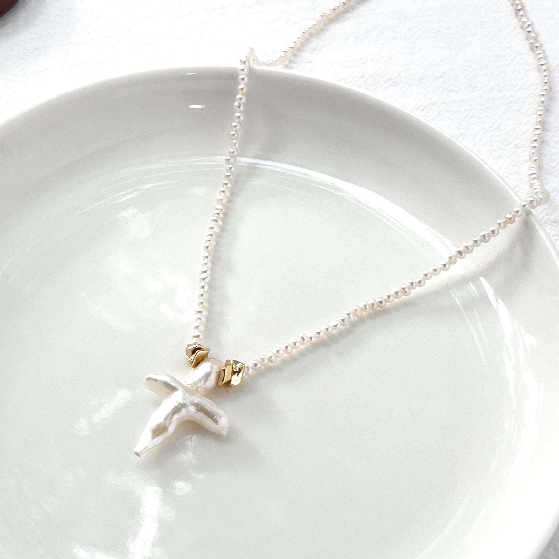 Necklace with a cross pendant on a white plate