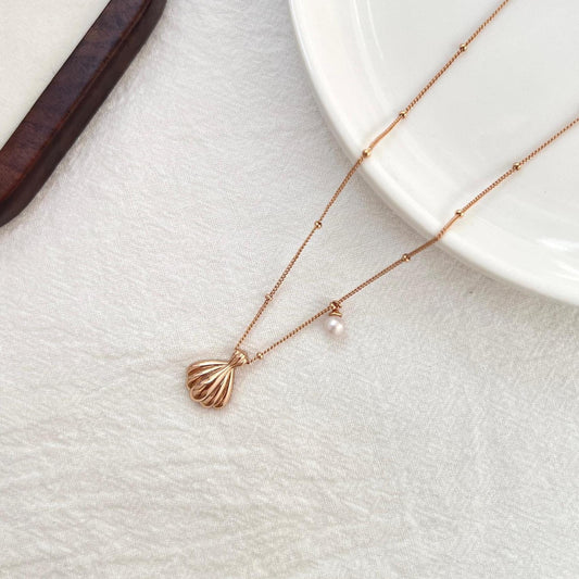 Front view of 18K gold shell pendant with freshwater pearl charm on a delicate chain
