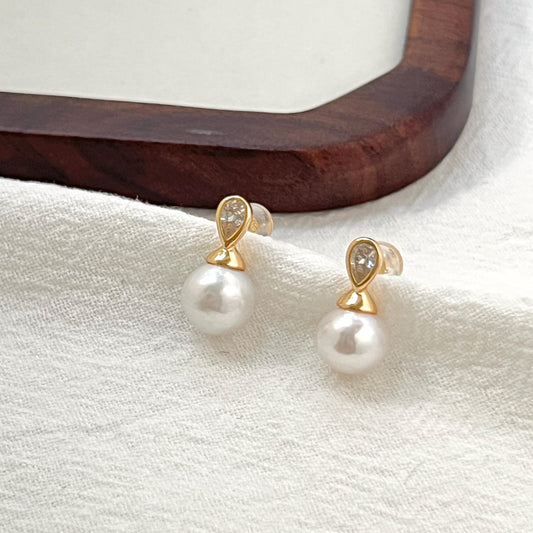 Close-up of 18K gold baroque pearl and crystal stud earrings showcasing pearl texture and sparkle of the crystal