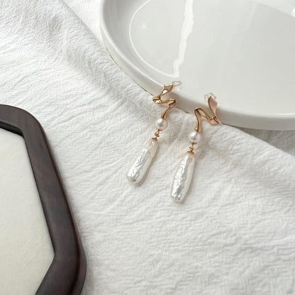 Close-up of baroque freshwater pearls on 18K gold bar drop earrings