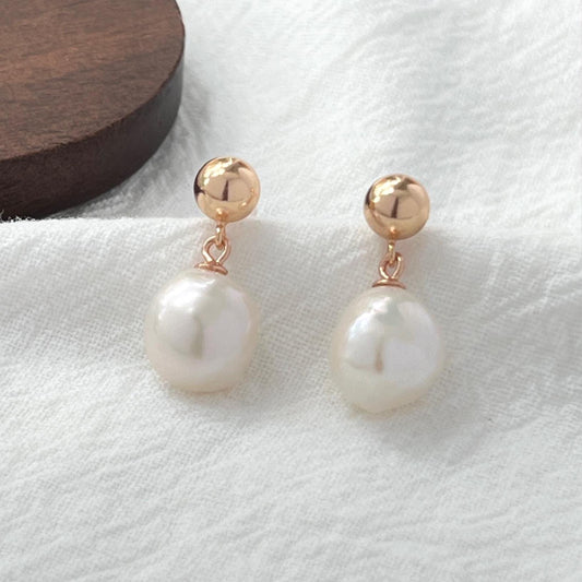 Close-up of natural baroque pearl on 18K gold teardrop earrings