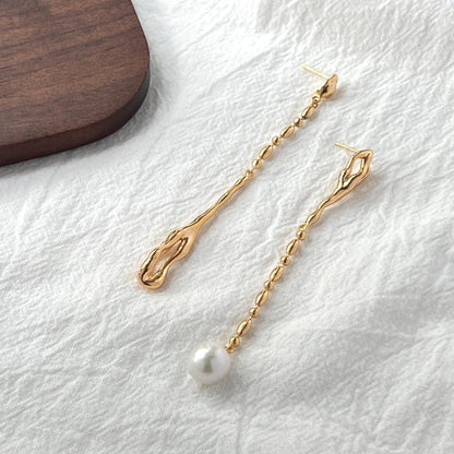 Close-up of natural freshwater pearls on 18K gold long drop mismatched earrings