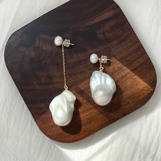 minimalist large freshwater baroque pearl asymmetrical earrings styled flatlay
