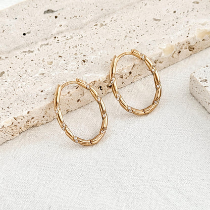 close up of 18k gold oval hoop earrings twisted rope design with sparkling cz accents
