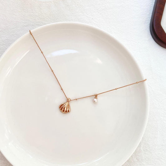 Side view showcasing the shell pendant and pearl drop on 18K gold necklace