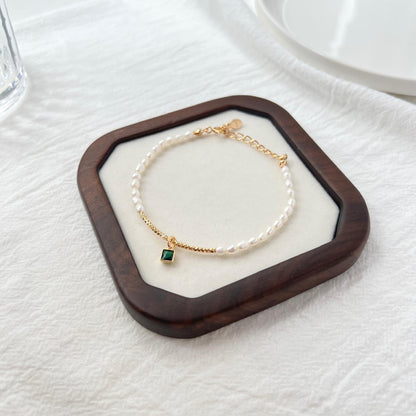 Close-up of natural baroque pearls and green zircon beads on 18K gold bracelet