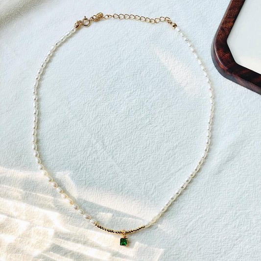 Detail of clasp and adjustable chain on 18K gold freshwater baroque pearl choker with green zircon, delicate minimalist jewellery.