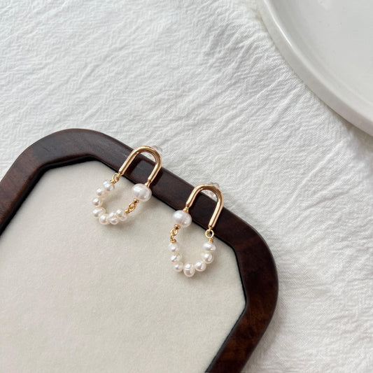Close-up of natural freshwater baroque pearls on 18K gold hoop earrings, delicate handcrafted minimalist jewelry.