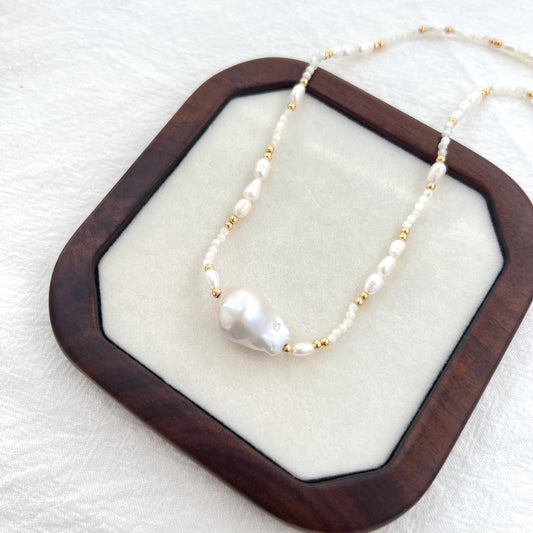 Close-up of natural baroque freshwater pearls and 18K gold beads on minimalist choker necklace.