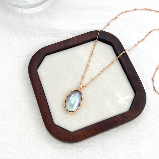 Close-up of natural Mabe pearl pendant set in 18K gold, vintage-inspired statement necklace detail.