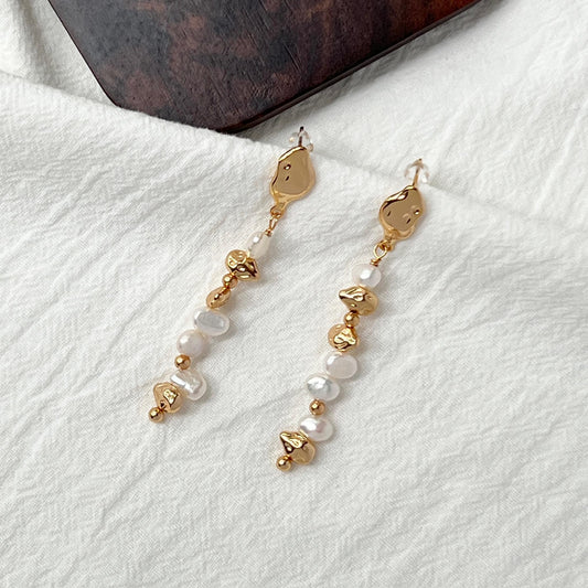 Close‑up of natural freshwater baroque pearls on 18K gold drop earrings, handcrafted delicate jewelry with vintage charm.