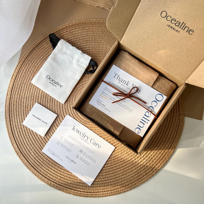 Ocealine Jewelry packaging with jewelry, care cards, and a box on a woven mat.
