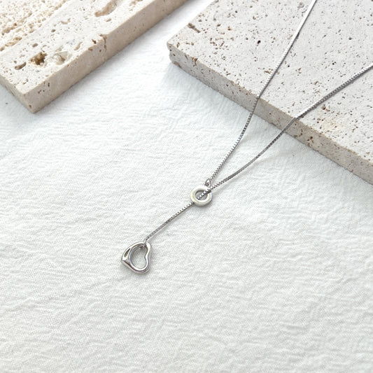 close up of sterling silver y lariat necklace heart charm texture and shine
