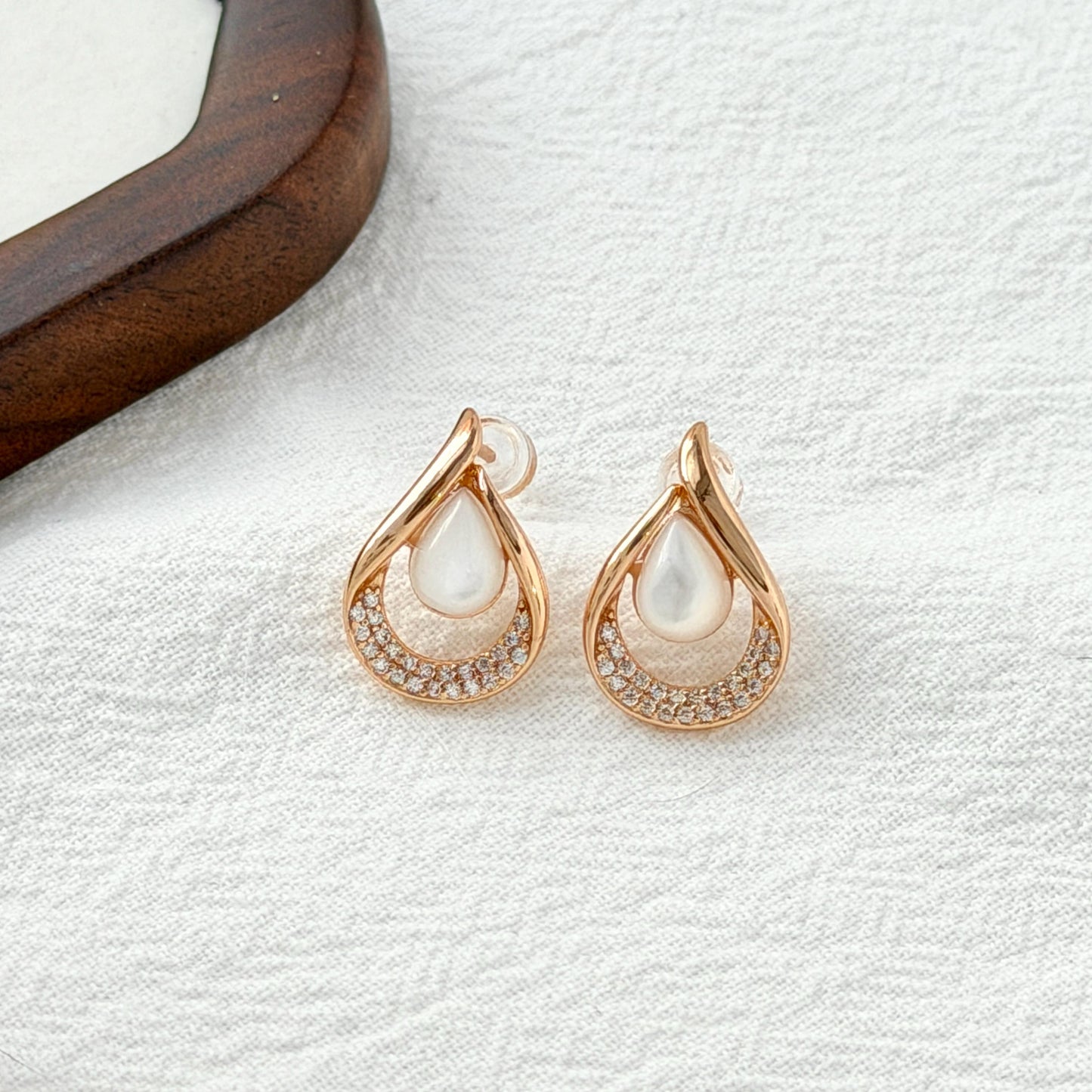 close up of 18k gold teardrop mother of pearl and cubic zirconia stud earrings
