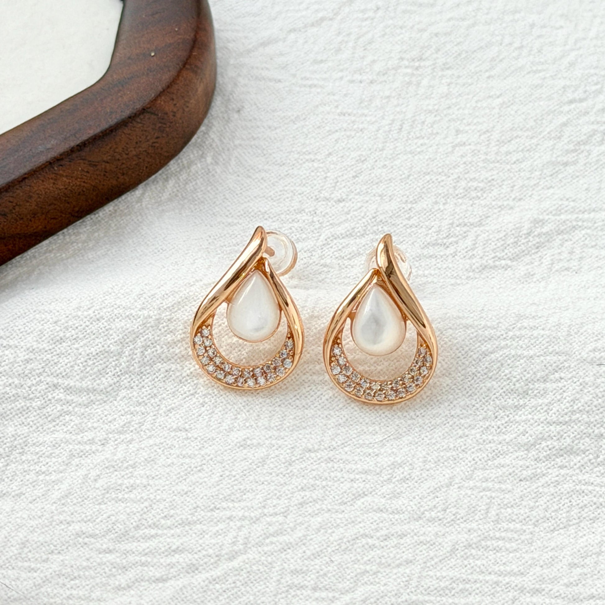 close up of 18k gold teardrop mother of pearl and cubic zirconia stud earrings
