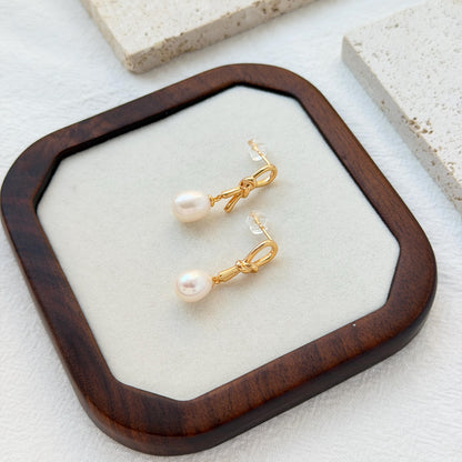 close up of 18k gold bow knot pearl drop earrings detailing and texture

