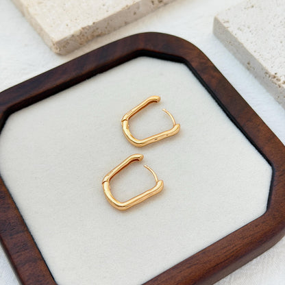 18k gold rectangular huggie hoop earrings on ear sleek everyday jewelry
