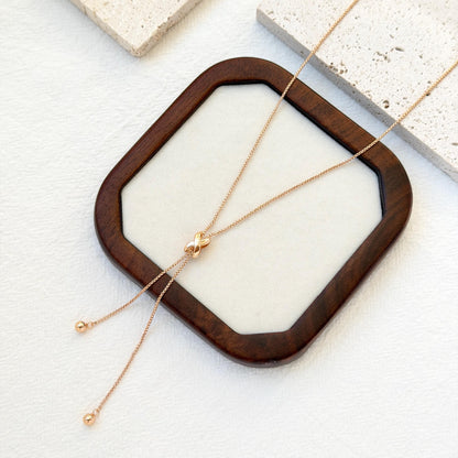 close up of 18k gold knot tassel necklace texture and design
