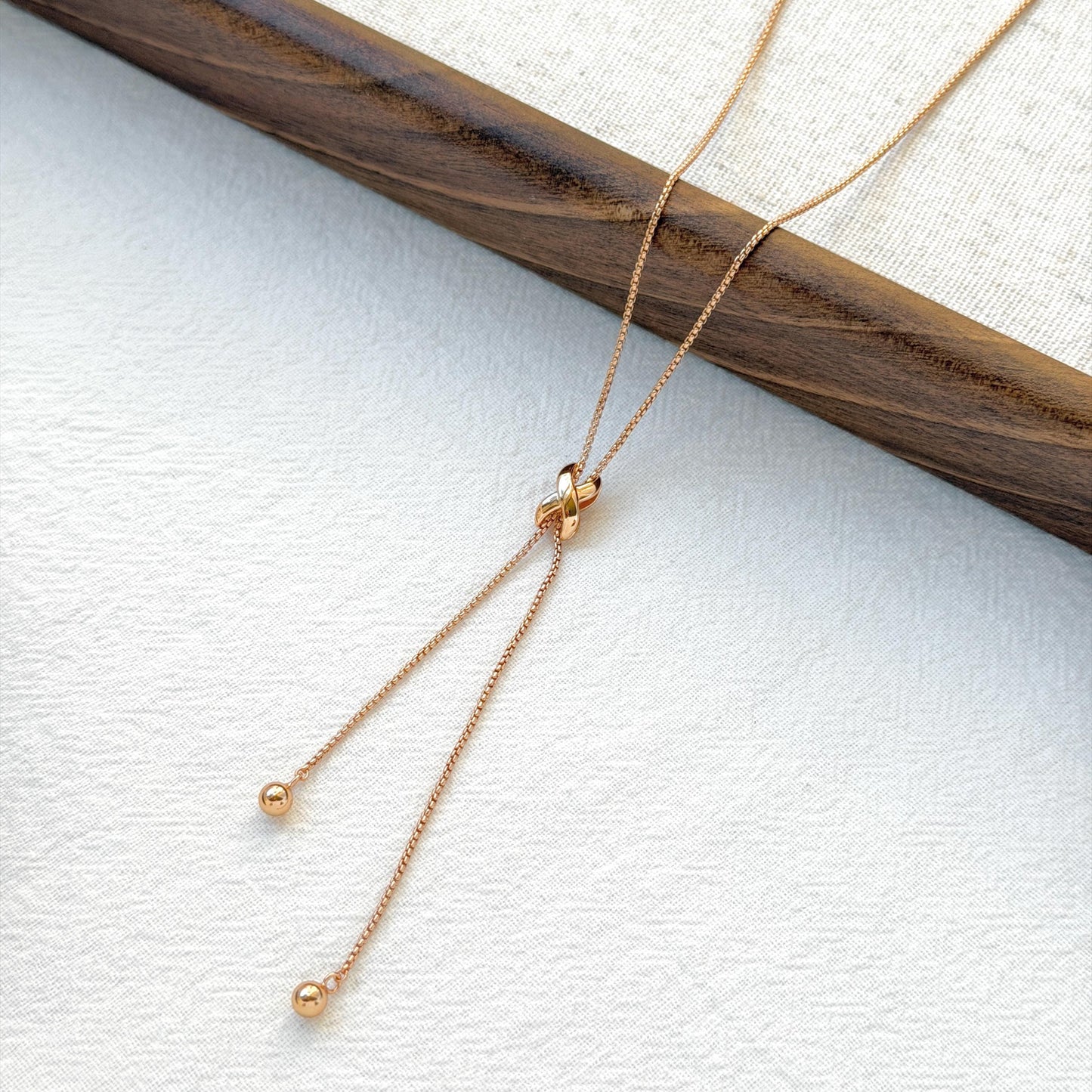 minimalist 18k gold knot tassel necklace styled flatlay jewelry
