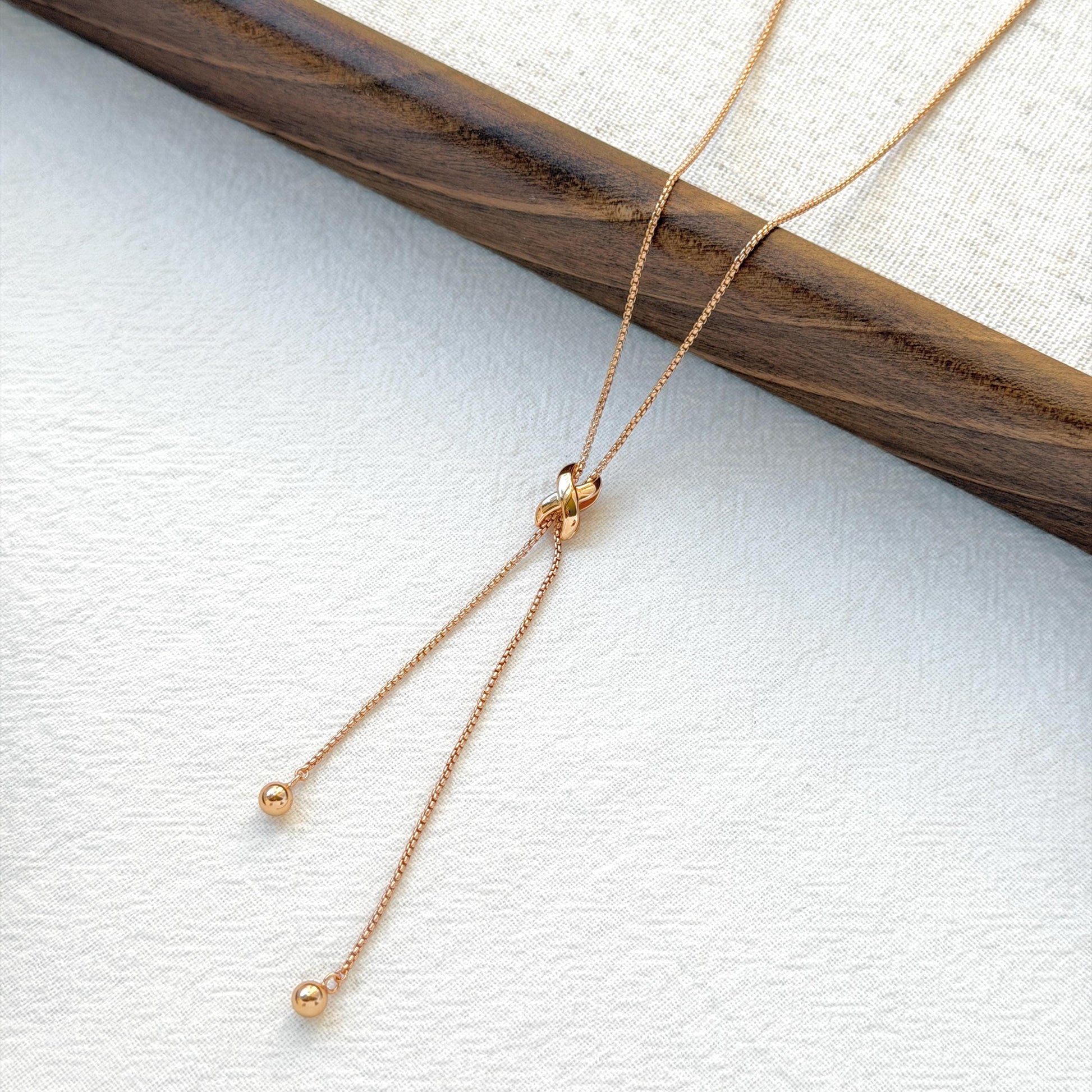 minimalist 18k gold knot tassel necklace styled flatlay jewelry
