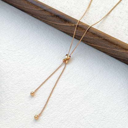 minimalist 18k gold knot tassel necklace styled flatlay jewelry
