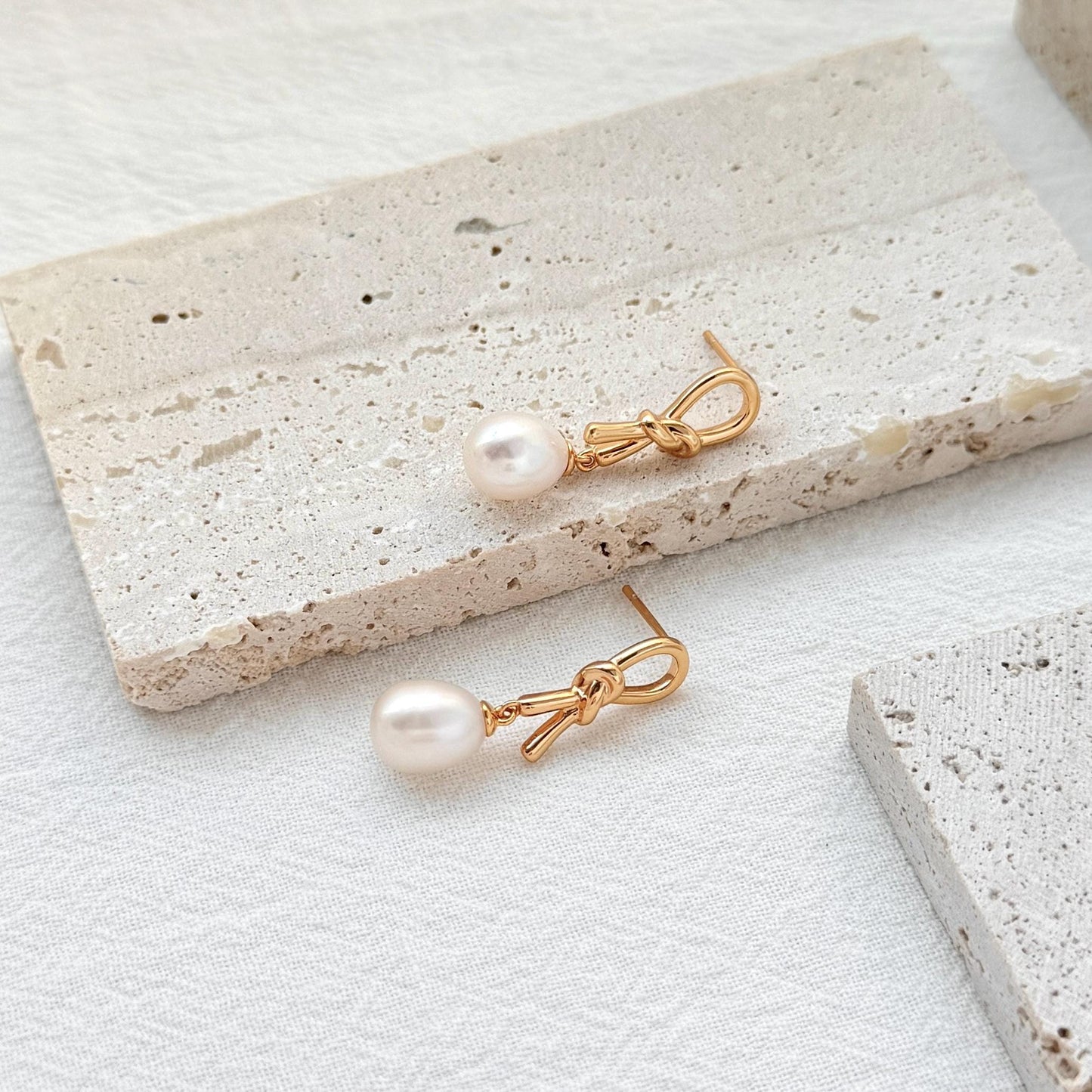 close up of 18k gold bow knot pearl drop earrings detailing and texture
