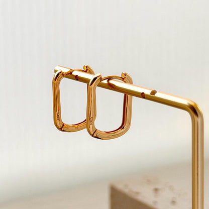 18k gold rectangular huggie hoop earrings on ear sleek everyday jewelry
