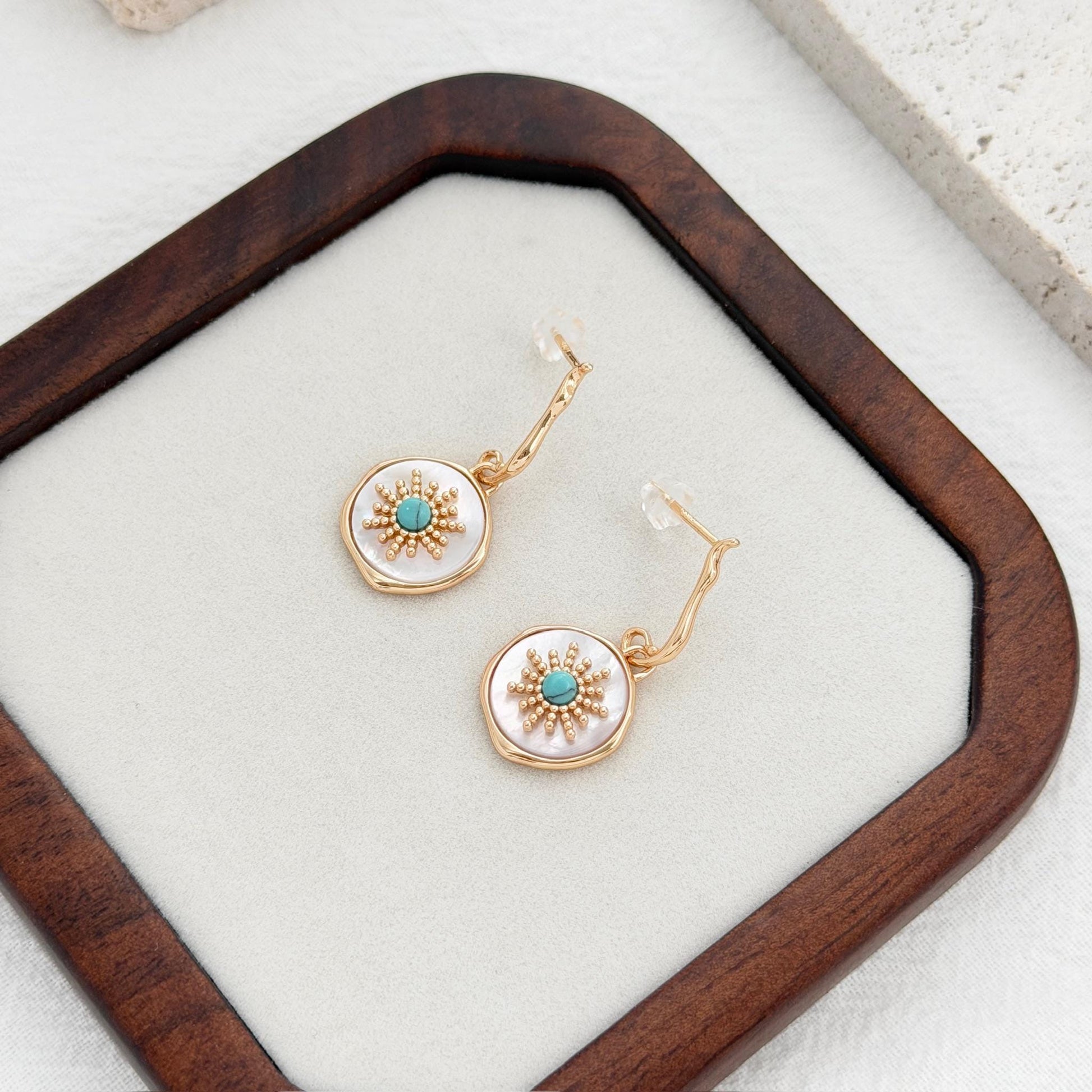 gold disc earrings with turquoise center and shell background sunburst style